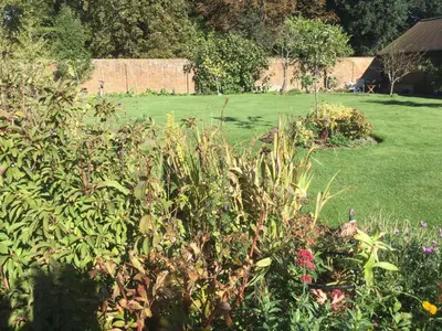 a garden with flowers and a field in the background at STACK YARD COTTAGE. in Cambridge