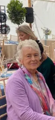 an older woman sitting in front of a table at STACK YARD COTTAGE. in Cambridge