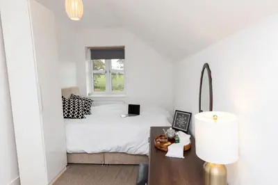 a bedroom with a bed and a desk with a lamp at The Poppies Cottage in Six Mile Bottom