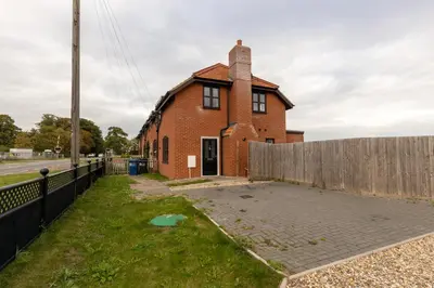 an old brick house with a fence around it at The Poppies Cottage in Six Mile Bottom