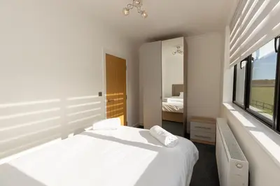 a white bedroom with a bed and a window at The Mayfair in Six Mile Bottom