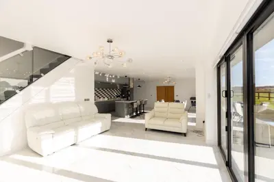 a living room with white furniture and a staircase at The Mayfair in Six Mile Bottom