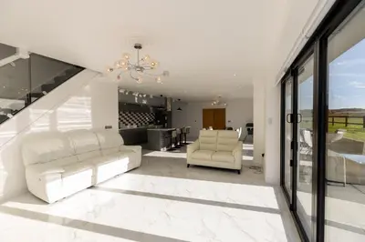a living room with a white couch and a chandelier at The Mayfair in Six Mile Bottom