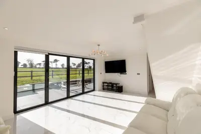 a living room with a white couch and a tv at The Mayfair in Six Mile Bottom
