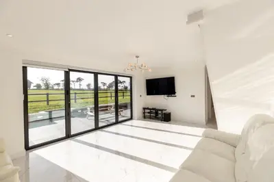 a living room with a white couch and a tv at The Mayfair in Six Mile Bottom