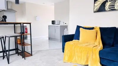 a living room with a blue couch and a yellow blanket at Newmarket - Suffolk Flat with Garden EV in Newmarket