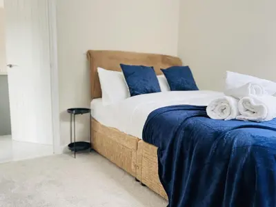 a bedroom with a bed with blue and white pillows at Newmarket - Suffolk Flat with Garden EV in Newmarket