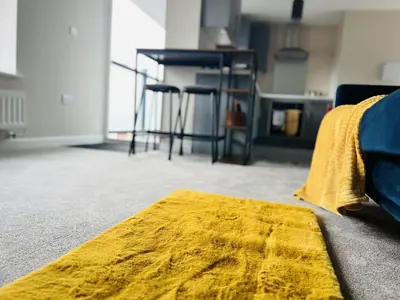 a yellow rug sitting on the floor in a living room at Newmarket - Suffolk Flat with Garden EV in Newmarket