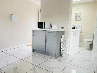 a kitchen with a counter with a microwave and a toilet at Newmarket - Suffolk Flat with Garden EV in Newmarket