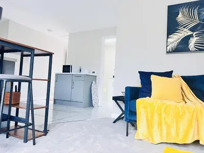 a living room with a blue chair and a yellow blanket at Newmarket - Suffolk Flat with Garden EV in Newmarket