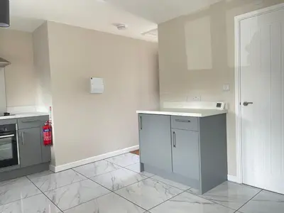 a white kitchen with a sink and a stove at Newmarket - Suffolk Flat with Garden EV in Newmarket