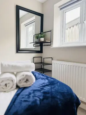 a bedroom with a mirror and towels on a bed at Newmarket - Suffolk Flat with Garden EV in Newmarket