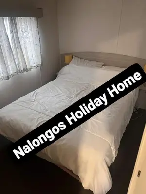 a bed with a black and white blanket on it at FV006 NALONGOS HOLIDAY HOME in Saint Osyth