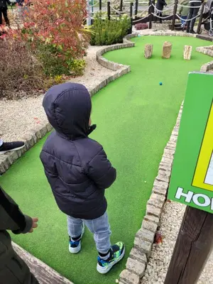 a young child standing on a miniature golf course at FV006 NALONGOS HOLIDAY HOME in Saint Osyth