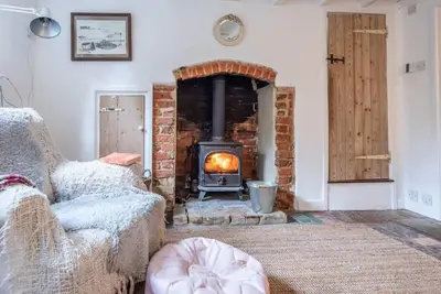 a living room with a brick fireplace with a stove at Lilac Cottage, Wenhaston in Halesworth