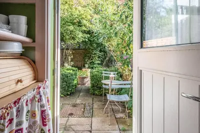 an open door to a patio with a table and chairs at Lilac Cottage, Wenhaston in Halesworth