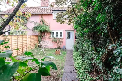 a pink house with a white door in a yard at Lilac Cottage, Wenhaston in Halesworth