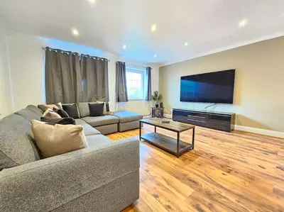 a living room with a couch and a flat screen tv at Spacious 4 Bedroom, Free Parking, Sleeps 7 in Havering atte Bower