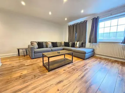 a living room with a couch and a table at Spacious 4 Bedroom, Free Parking, Sleeps 7 in Havering atte Bower