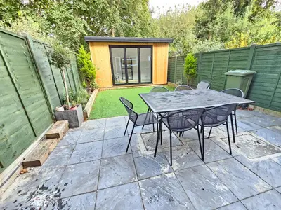a patio with a table and chairs in a backyard at Spacious 4 Bedroom, Free Parking, Sleeps 7 in Havering atte Bower