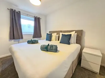 a bedroom with a large white bed with blue pillows at Spacious 4 Bedroom, Free Parking, Sleeps 7 in Havering atte Bower