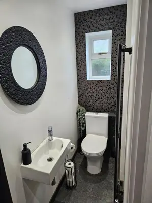 a bathroom with a toilet and a sink and a mirror at Spacious 4 Bedroom, Free Parking, Sleeps 7 in Havering atte Bower