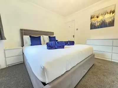 a bedroom with a large white bed with blue pillows at Spacious 4 Bedroom, Free Parking, Sleeps 7 in Havering atte Bower