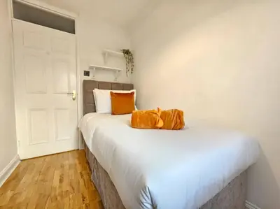 a bedroom with a white bed with an orange bag on it at Spacious 4 Bedroom, Free Parking, Sleeps 7 in Havering atte Bower