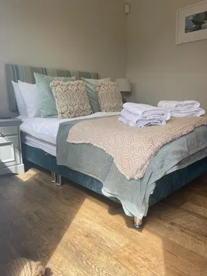 a bed with a blanket and pillows on it at The Courtyard Rooms in Brightlingsea