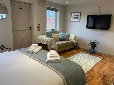 a bedroom with a bed and a couch and a television at The Courtyard Rooms in Brightlingsea