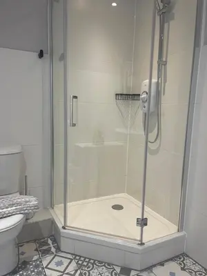 a shower with a glass door in a bathroom at The Courtyard Rooms in Brightlingsea