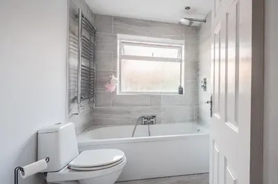 a white bathroom with a toilet and a bath tub at SuffStay in Ipswich