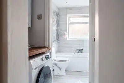 a white bathroom with a toilet and a bath tub at SuffStay in Ipswich