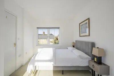 a white bedroom with a bed and a window at Luxurious 3 Bed House with Free Parking, Sky TV, Movies & Netflix in Braintree