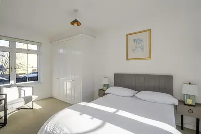 a white bedroom with a bed and a desk and window at Luxurious 3 Bed House with Free Parking, Sky TV, Movies & Netflix in Braintree