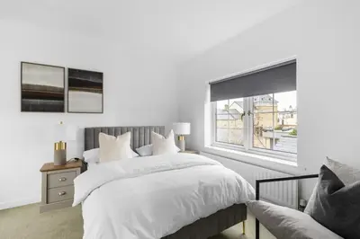a white bedroom with a bed and a window at Luxurious 3 Bed House with Free Parking, Sky TV, Movies & Netflix in Braintree
