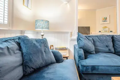 a living room with a blue couch and a table at Seaway Cottage, Aldeburgh in Aldeburgh