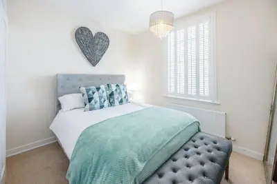 a bedroom with a bed with a blue tufted headboard at Seaway Cottage, Aldeburgh in Aldeburgh