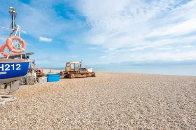 a boat and a bulldozer on a pebble beach at Seaway Cottage, Aldeburgh in Aldeburgh