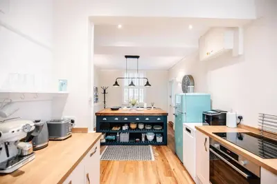 a kitchen with white cabinets and a blue refrigerator at Seaway Cottage, Aldeburgh in Aldeburgh