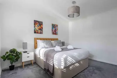 a white bedroom with a bed and a potted plant at The Orange House Langdon Hills in Langdon Hills
