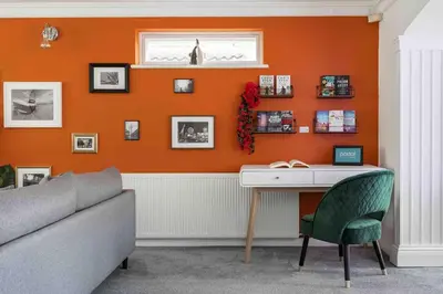 a living room with an orange wall with a desk at The Orange House Langdon Hills in Langdon Hills