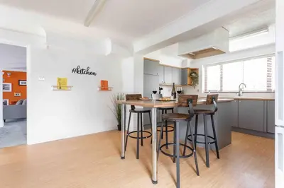 a kitchen with a table and stools in a room at The Orange House Langdon Hills in Langdon Hills