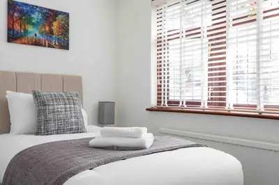 a bedroom with a bed with white sheets and a window at The Orange House Langdon Hills in Langdon Hills