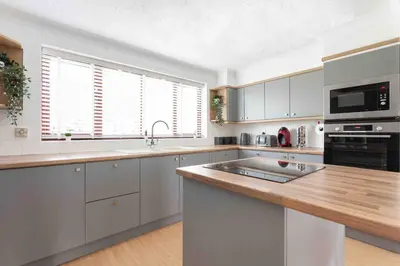 a kitchen with white cabinets and a wooden counter top at The Orange House Langdon Hills in Langdon Hills