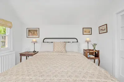a white bedroom with a large bed with two tables at The Red Shed Entire home for 2 Private garden and parking 2 miles from Bury St Edmunds in Whepstead