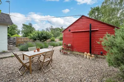 a red shed with a table and chairs in front of it at The Red Shed Entire home for 2 Private garden and parking 2 miles from Bury St Edmunds in Whepstead
