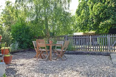 a wooden table and chairs in a yard with a fence at The Red Shed Entire home for 2 Private garden and parking 2 miles from Bury St Edmunds in Whepstead