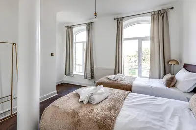 two beds in a room with two windows at Entire 3 Bedroom House Contractors Families Relocators in Ware