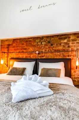 a bedroom with two beds and a brick wall at Entire 3 Bedroom House Contractors Families Relocators in Ware